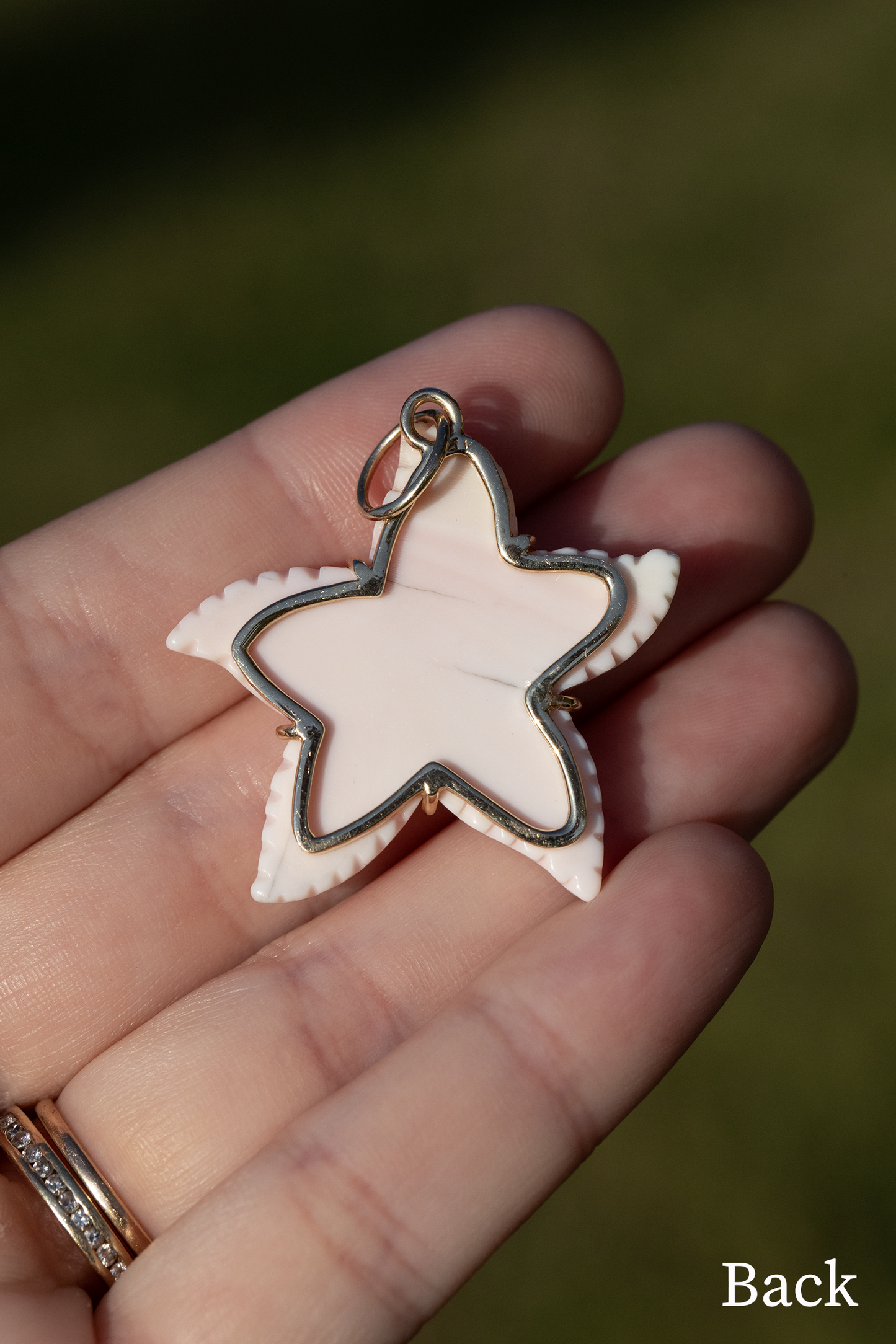 Star-shaped pendant held in a hand with a blurred natural background