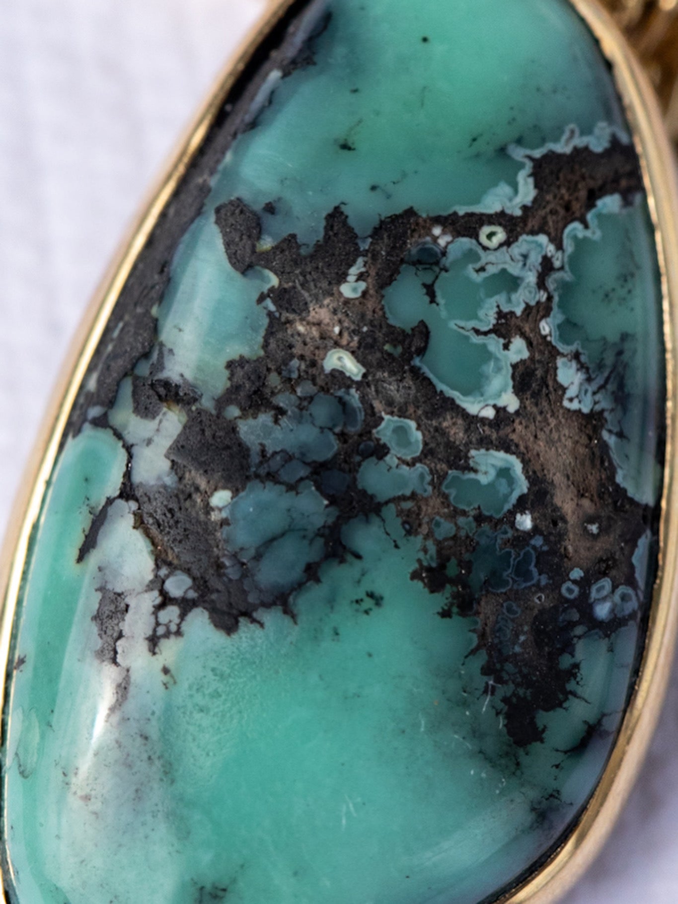 variscite stone with gold setting on a white background