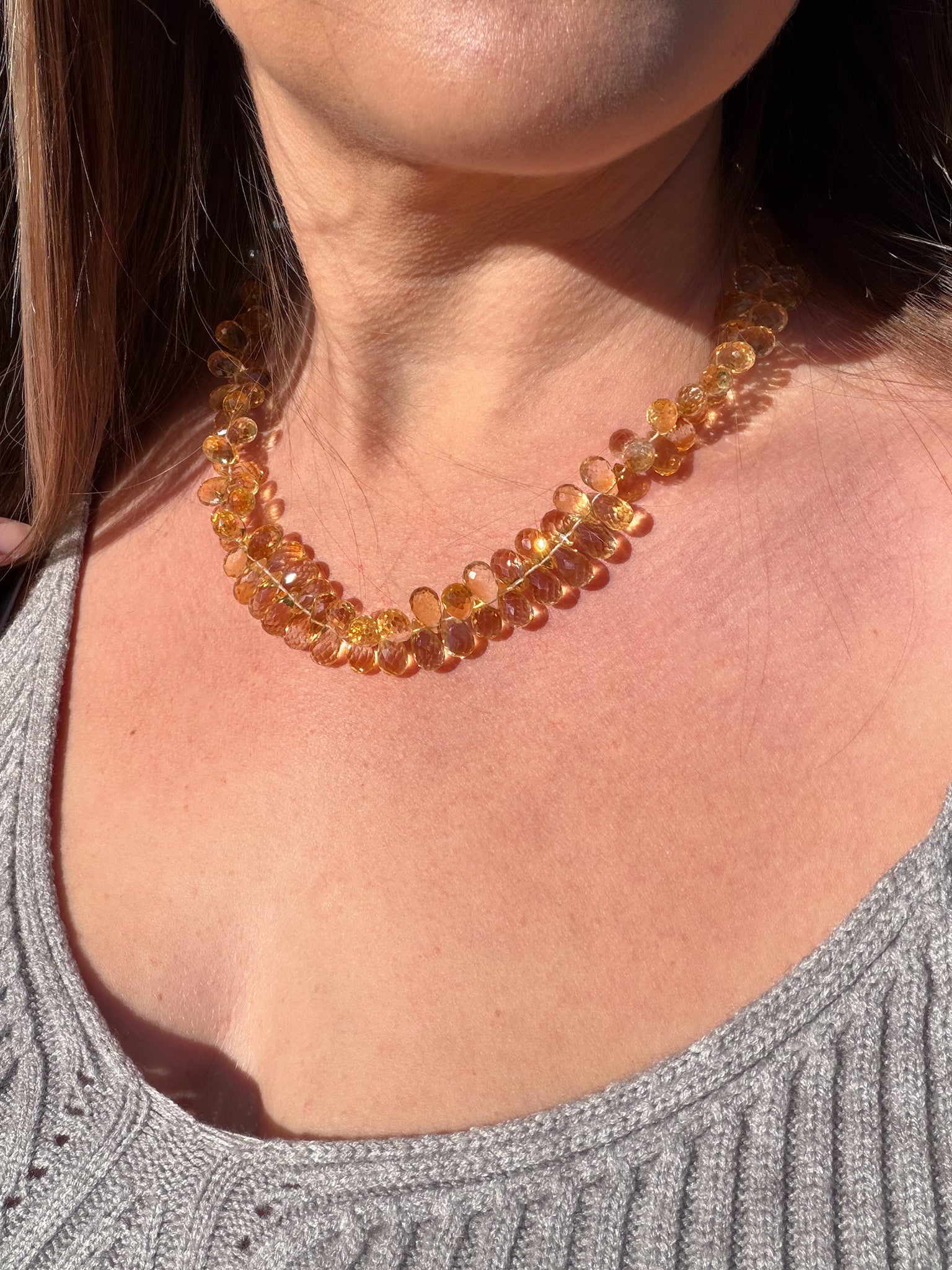 Close-up of a person wearing a citrine amber color  beaded necklace.