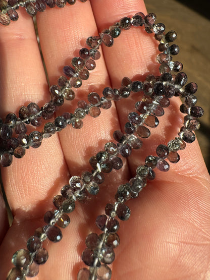Close-up of a string of small, faceted beads held between fingers.