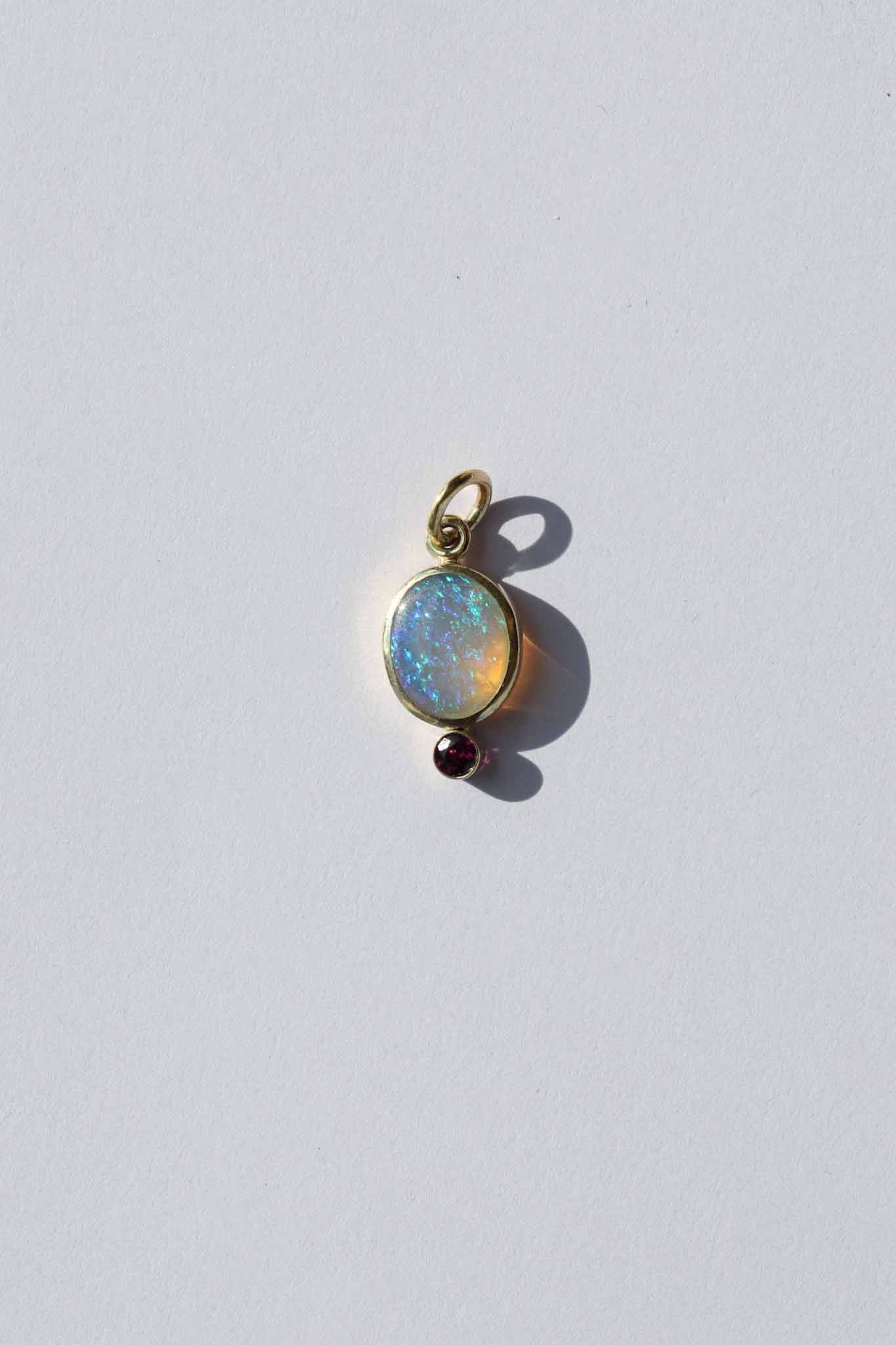 Opal pendant with a red gemstone on a white background
