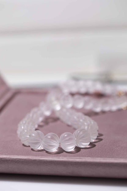 Set of clear beaded necklace on a pink surface with a blurred background