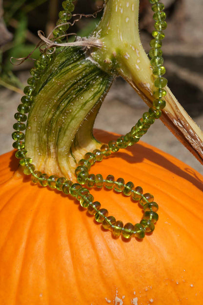 Green beaded necklace draped over a pumpkin with a blurred background