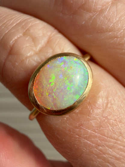 Gold ring with a colorful opal stone on a finger