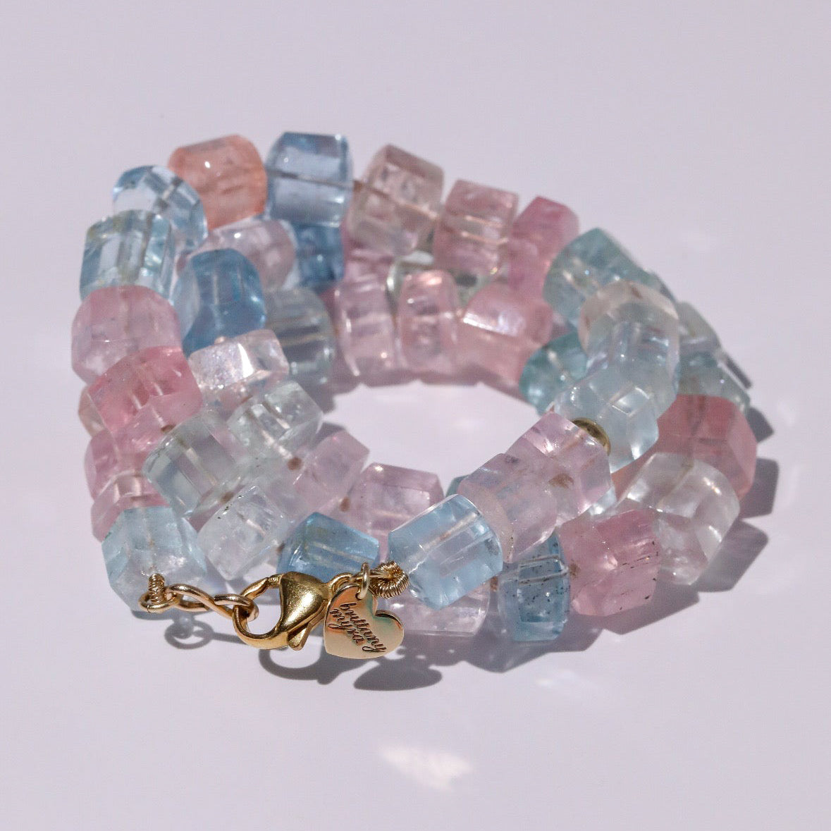 Detail of 14K gold lobster clasp with engraved heart tag on aquamarine necklace