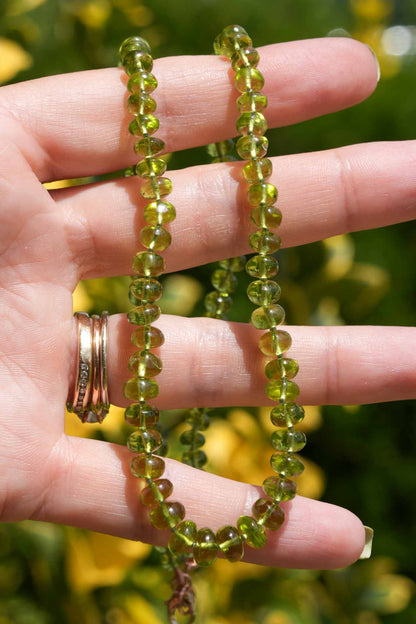 Green beaded bracelet on a hand with a blurred natural background