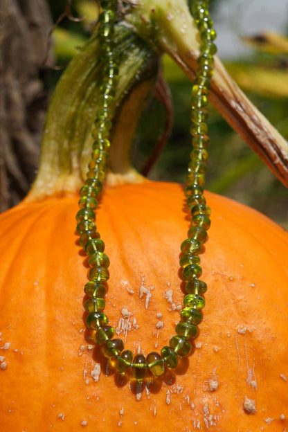 Green beaded necklace on a pumpkin with a blurred natural background