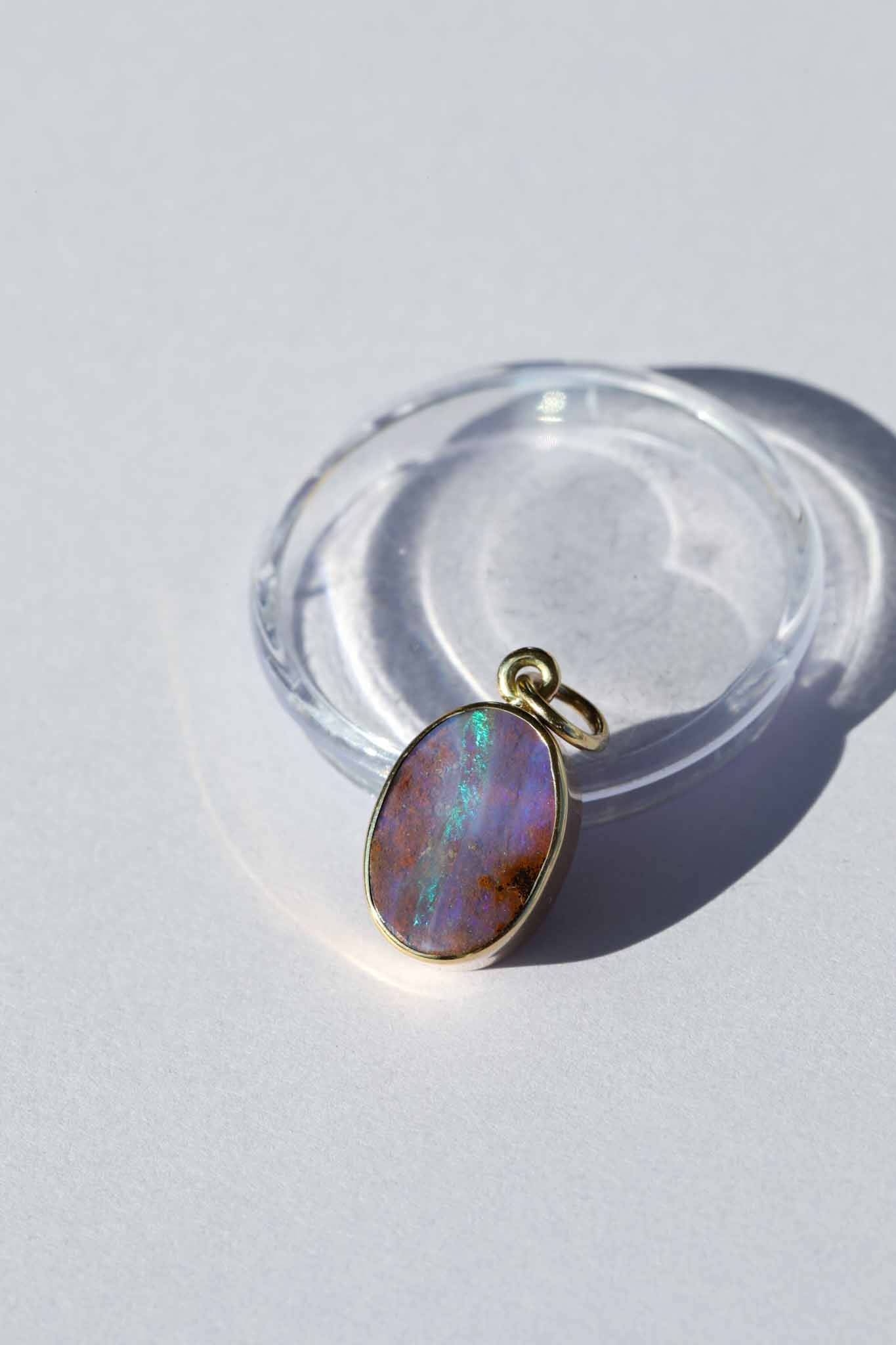 Opal pendant on a clear stand against a light background