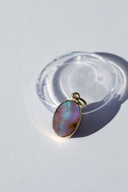 Opal pendant on a clear stand against a light background