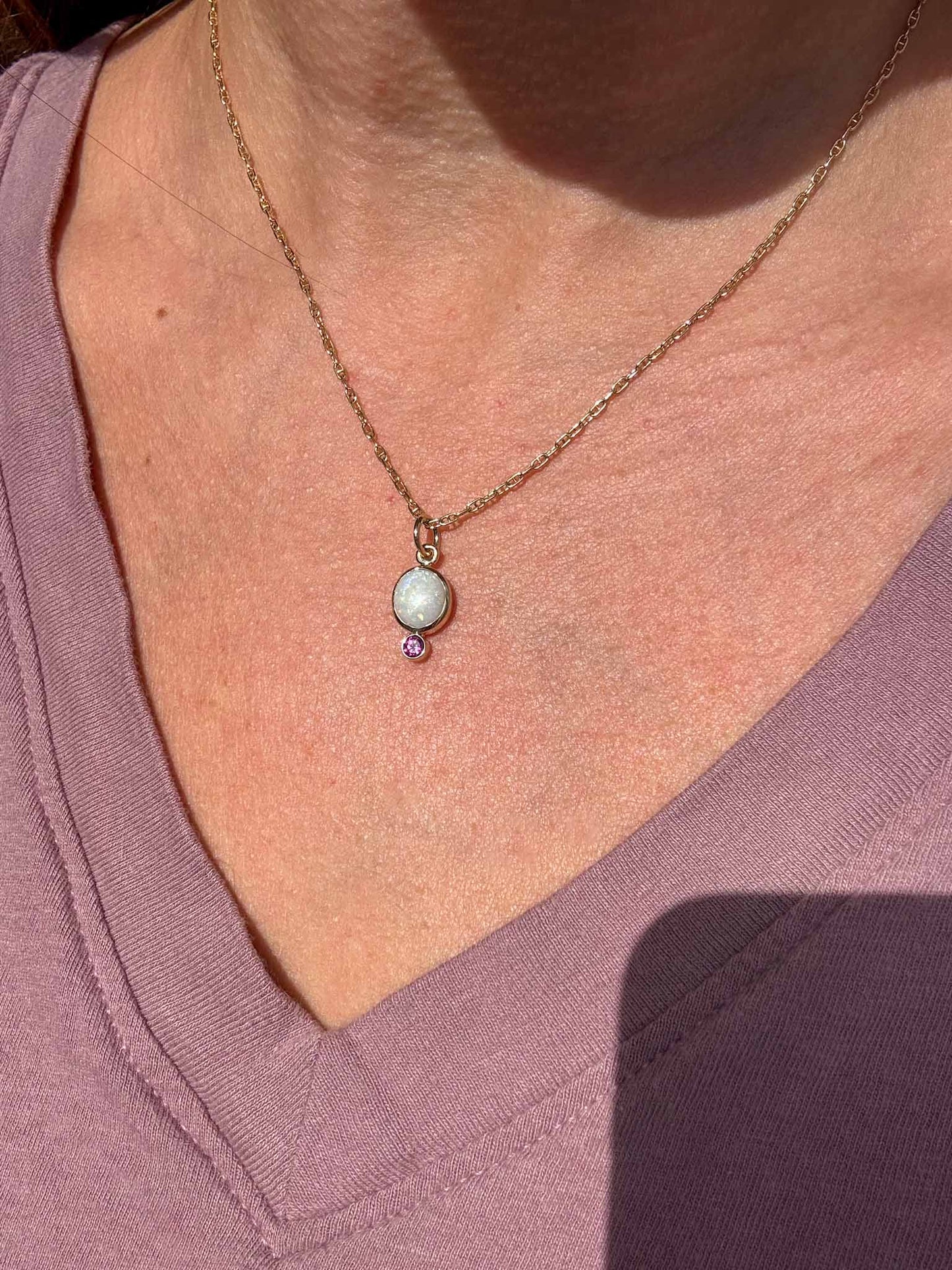 Necklace with a pendant on a person wearing a purple shirt