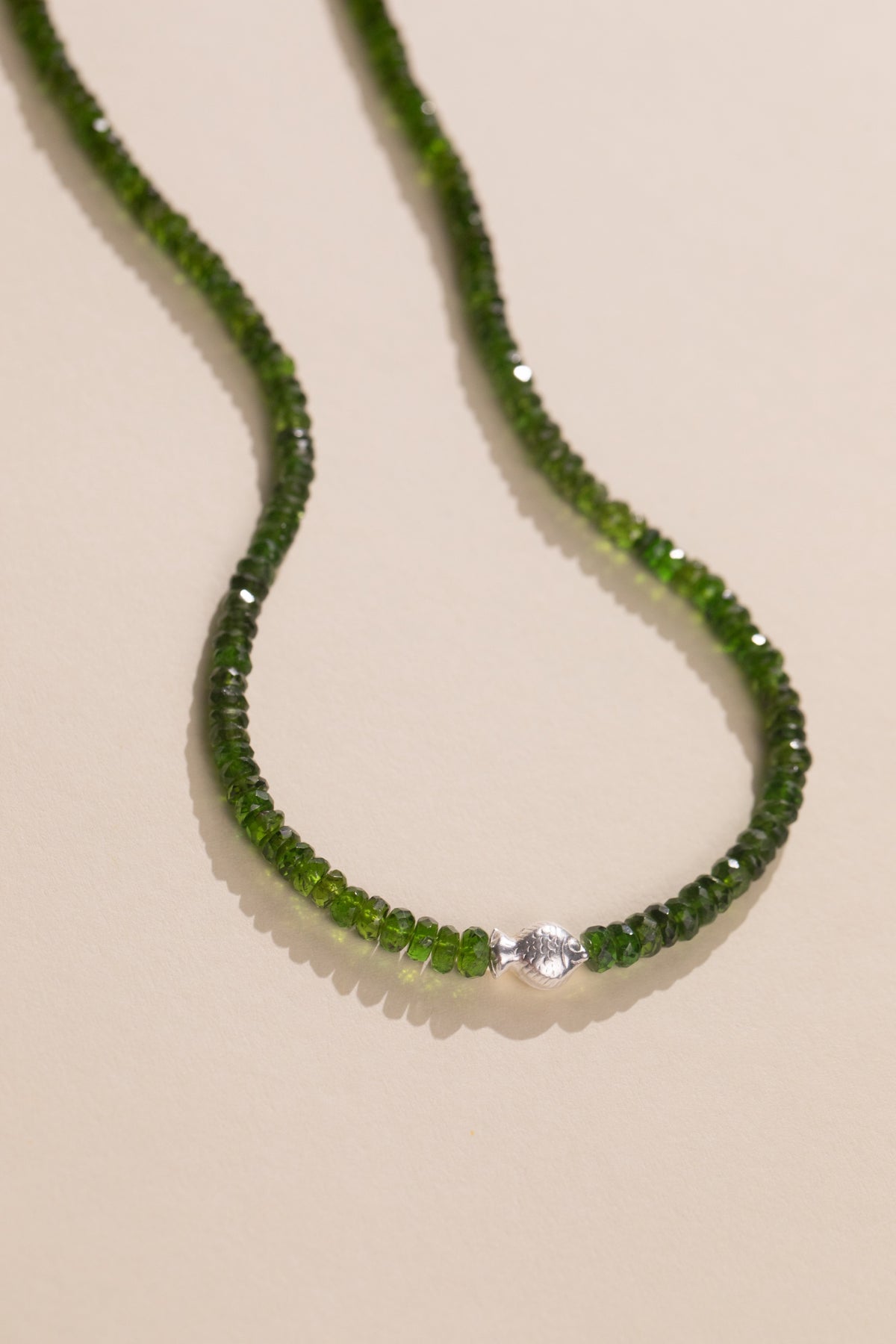 Sterling silver fish set sideways in a faceted chrome diopside strand, view 2
