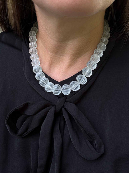 Clear beaded necklace worn by a person against a black background Carved Quartz Pumpkins 14k Gold Knotted Candy Bead Necklace