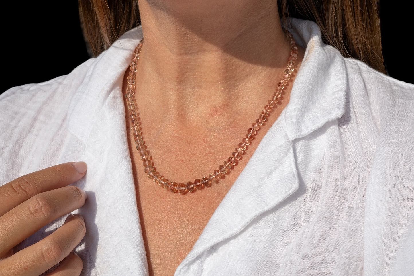 Person wearing a rose gold beaded necklace with a white shirt. genuine oregon sunstone peach red schiller beaded gemstone necklace fine 14k gold jewelry minimalist necklace