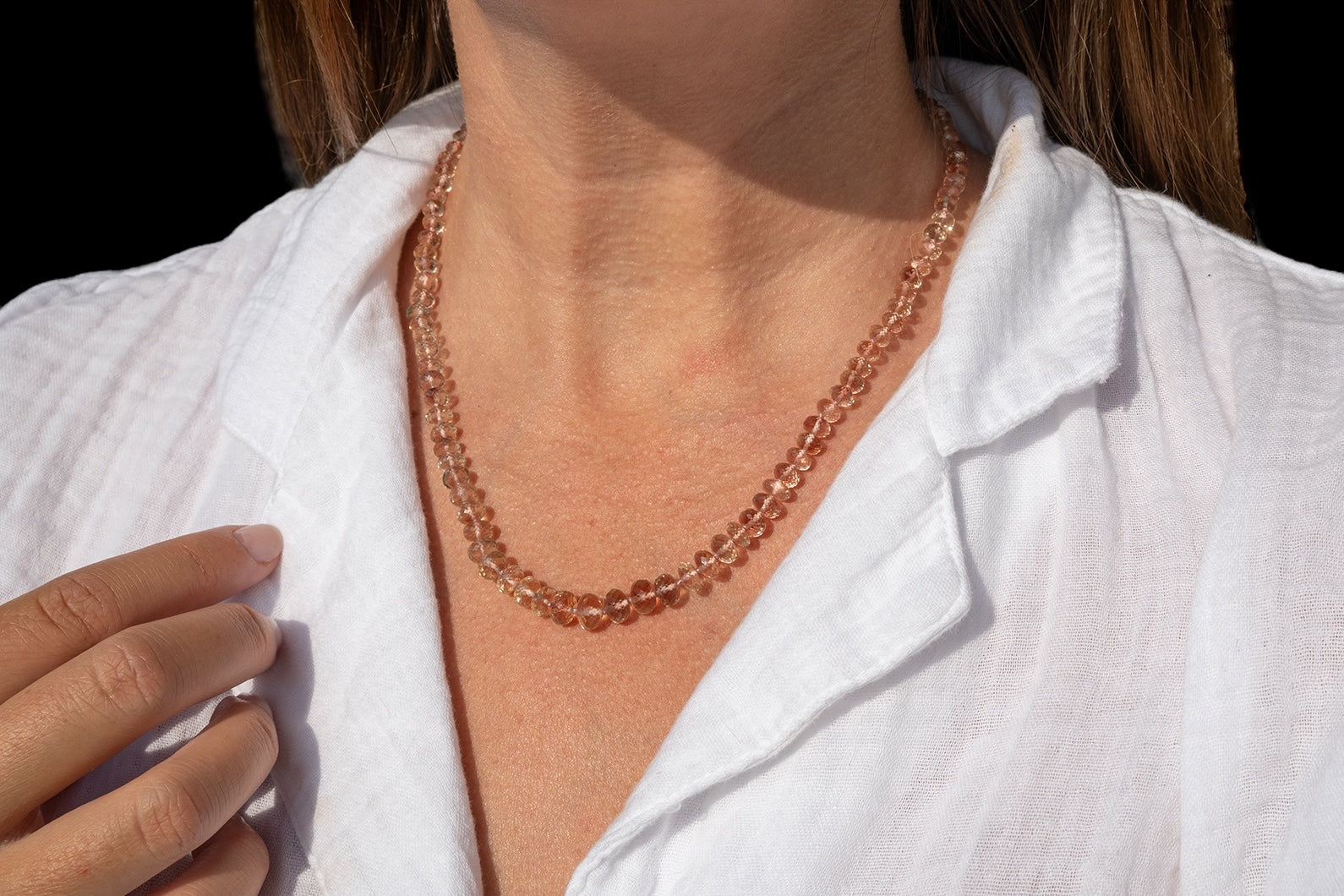 Person wearing a rose gold beaded necklace with a white shirt. genuine oregon sunstone peach red schiller beaded gemstone necklace fine 14k gold jewelry minimalist necklace