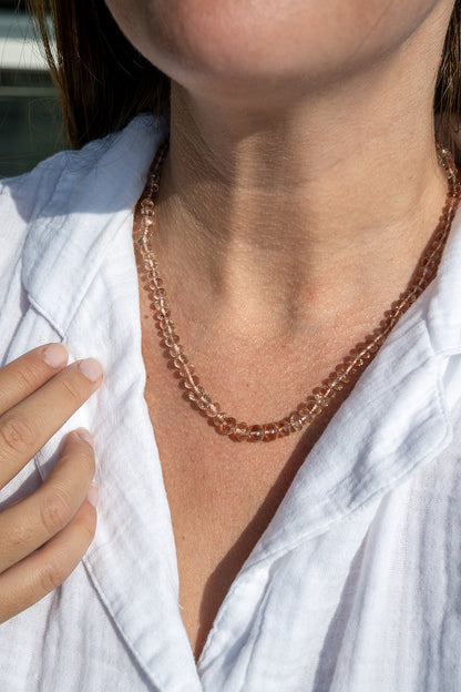 Close-up of a person wearing a rose gold necklace with a white shirt. genuine oregon sunstone peach red schiller beaded gemstone necklace fine 14k gold jewelry minimalist necklace