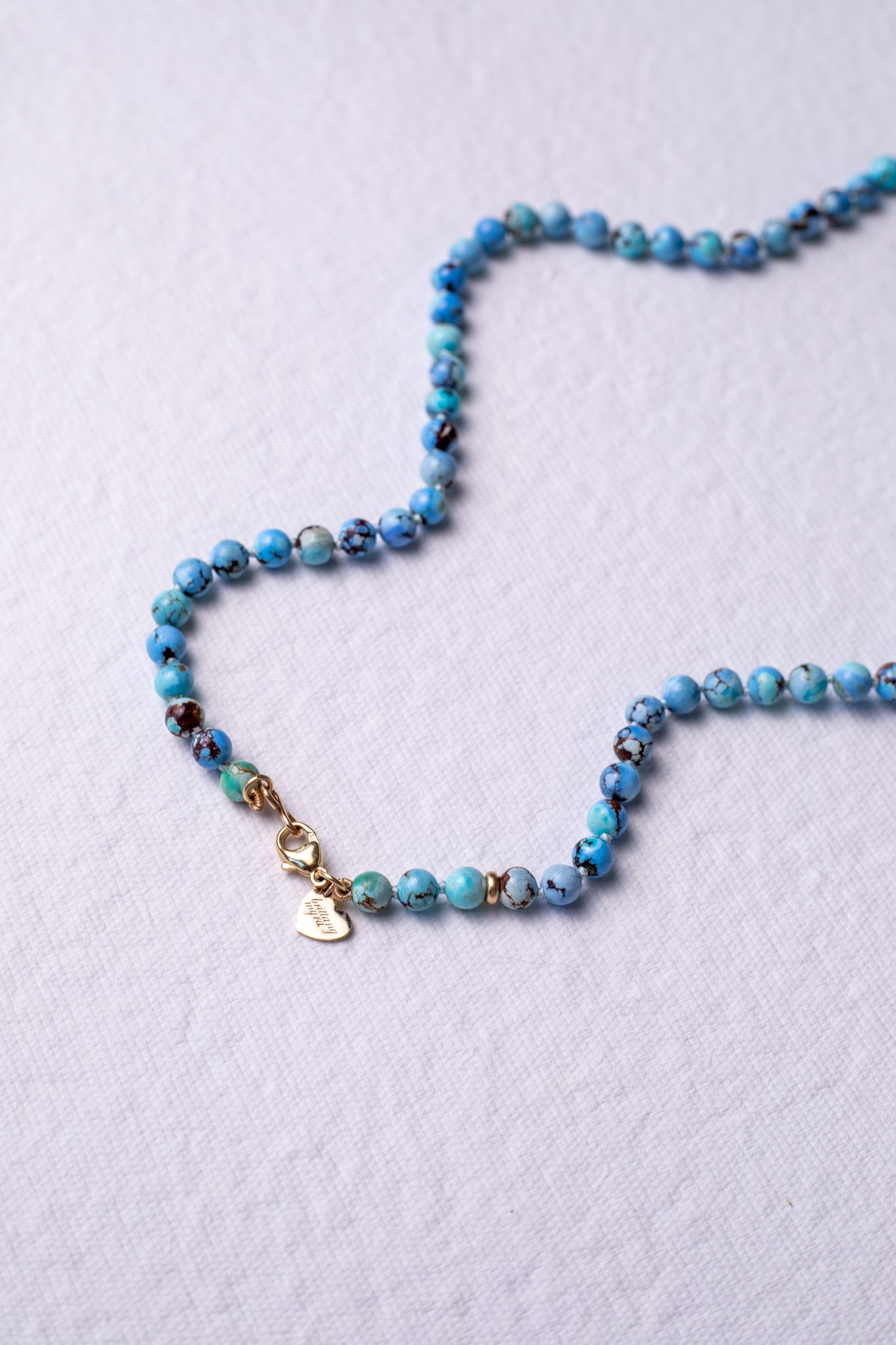 Golden hills turquoise gemstone strand necklace styled in a wave with gold heart tag