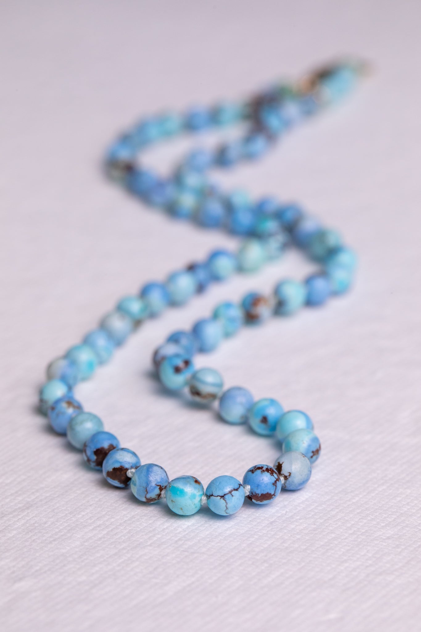 Kazakhstan turquoise hand knotted strand necklace in solid 14k gold laid flat on white linen