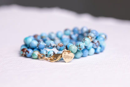 Lavender turquoise strand coiled to show the solid 14k gold engraved heart tag