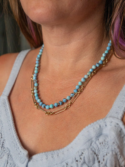 Woman wearing a lavender turquoise beaded necklace layered with delicate 14k gold chains