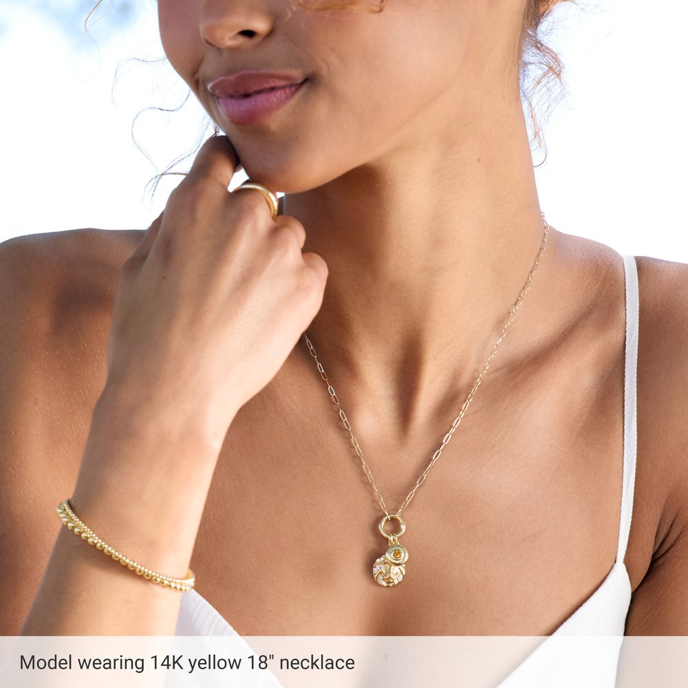 Woman wearing a gold necklace with a pendant, with text indicating the necklace's details.