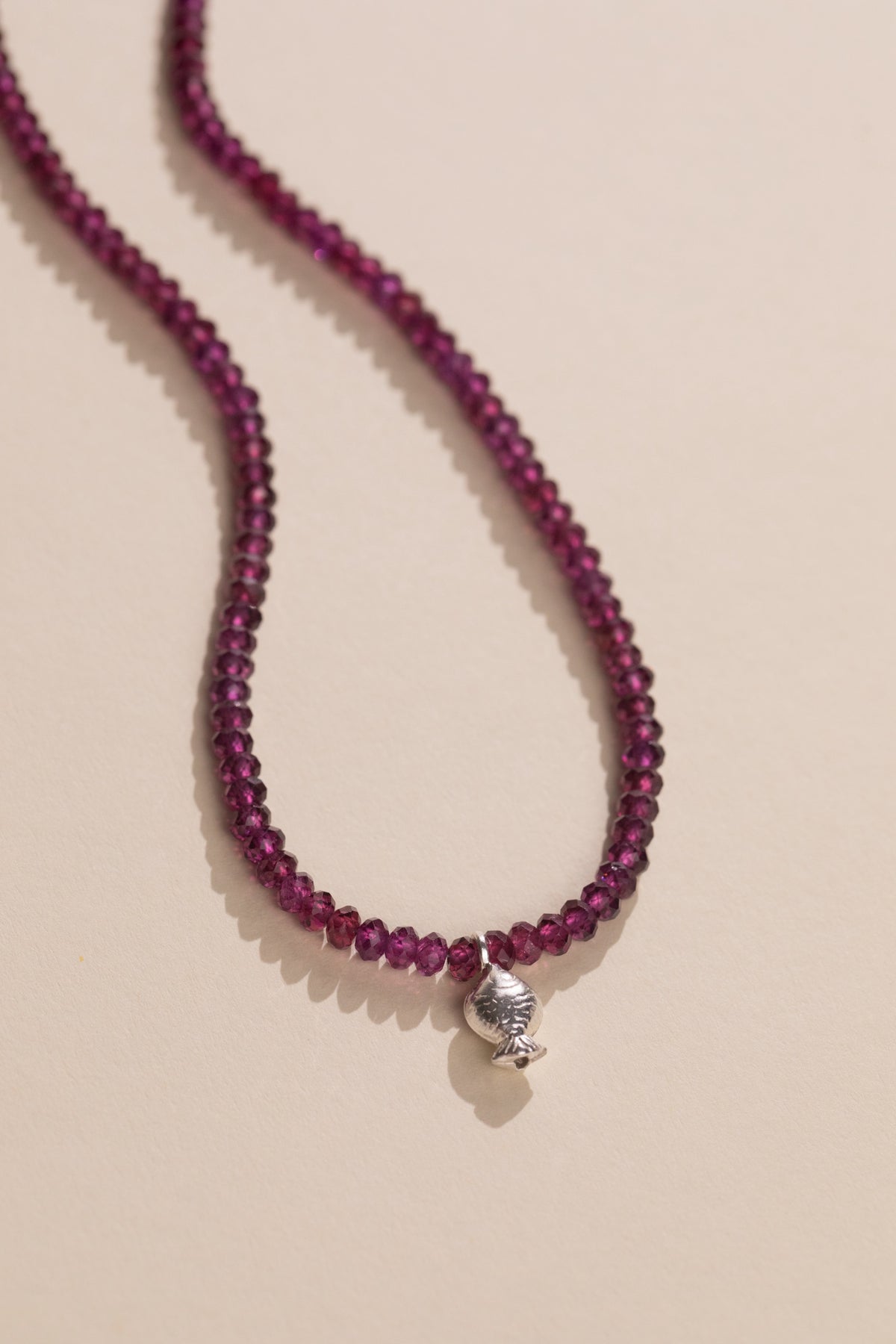 Faceted raspberry rhodolite garnet strand with a sterling silver Worry Fish, view 2
