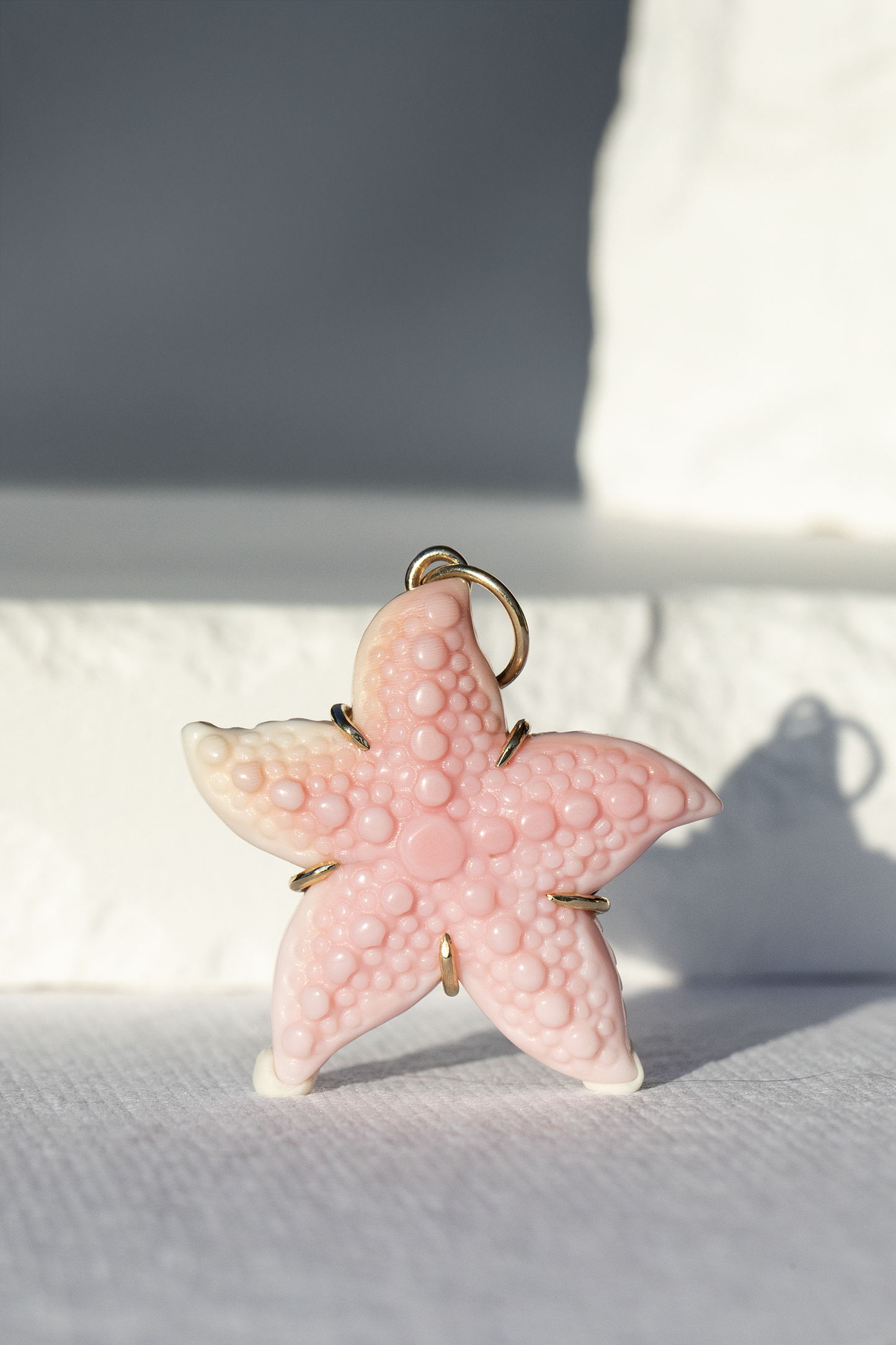 Pink starfish-shaped object with gold accents on a light background