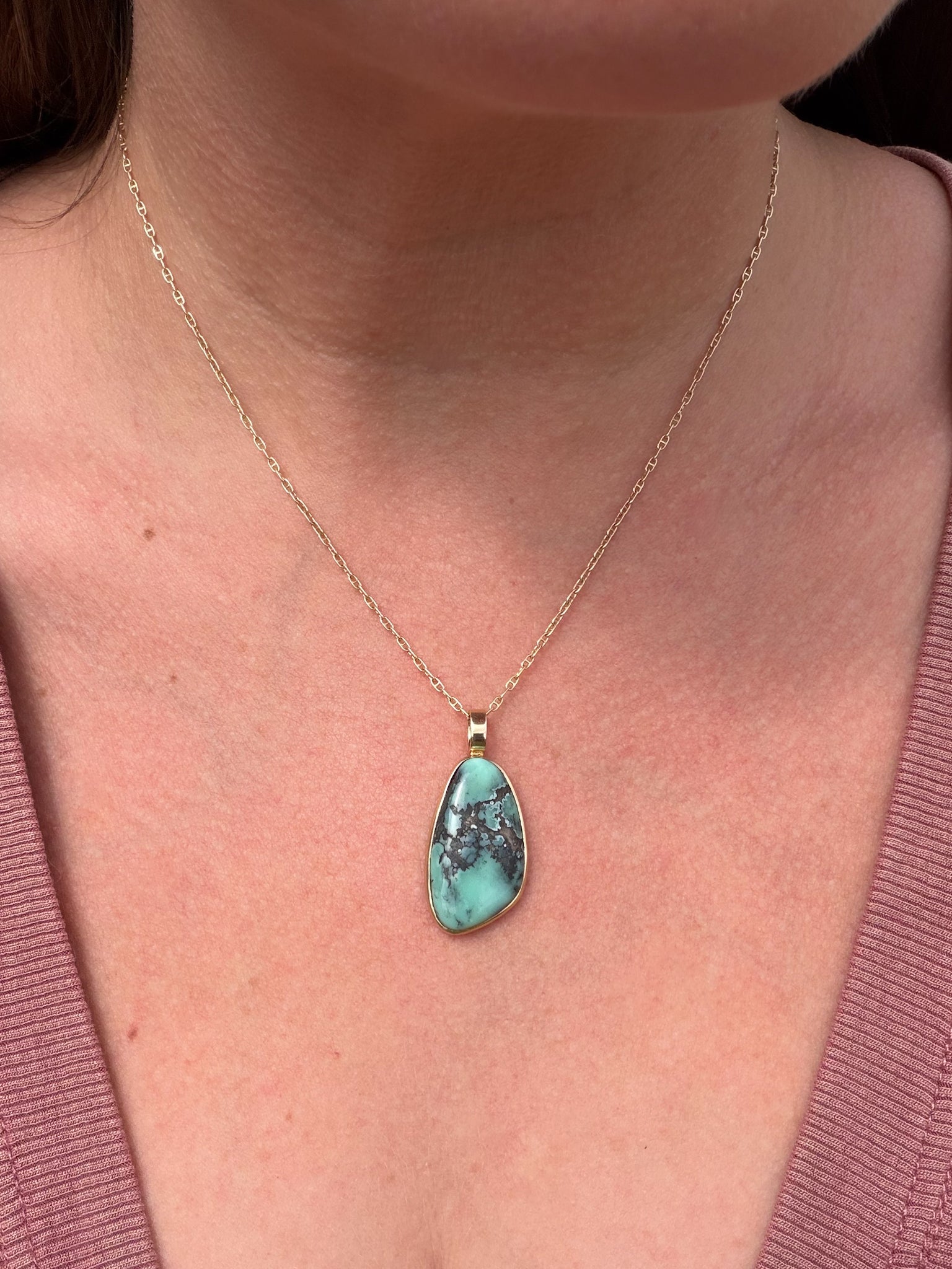 Freeform variscite cabochon pendant in 14k gold worn on a person at the collarbone
