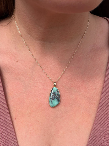 Freeform variscite cabochon pendant in 14k gold worn on a person at the collarbone